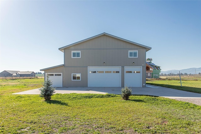 view of property exterior with a mountain view, a yard, a detached garage, fence, and concrete driveway