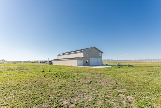 view of yard with a rural view, an outbuilding, and a detached garage