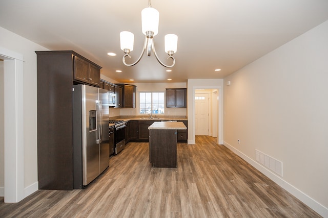 kitchen with a center island, appliances with stainless steel finishes, dark brown cabinetry, and pendant lighting