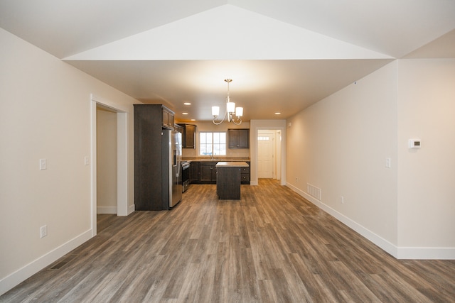 kitchen with dark brown cabinetry, stainless steel fridge, a kitchen island, dark hardwood / wood-style floors, and an inviting chandelier