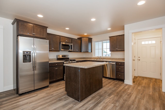 kitchen with wood-type flooring, stainless steel appliances, dark brown cabinetry, and a center island