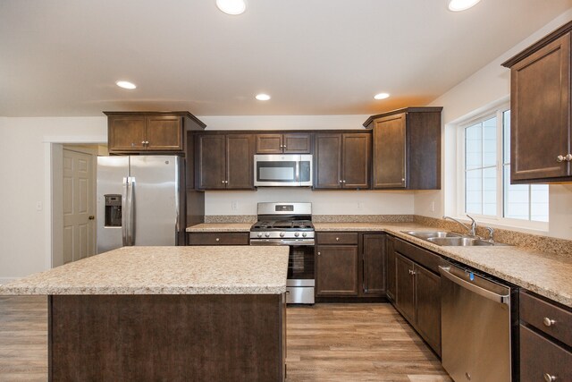 kitchen with stainless steel appliances, a center island, light hardwood / wood-style floors, sink, and dark brown cabinets