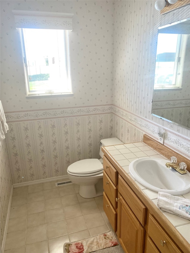 bathroom featuring a healthy amount of sunlight, vanity, toilet, and tile patterned floors