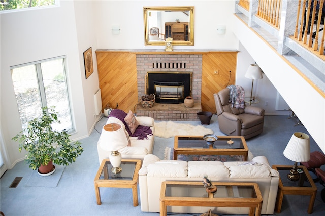 living room with wooden walls, a high ceiling, a fireplace, and a healthy amount of sunlight