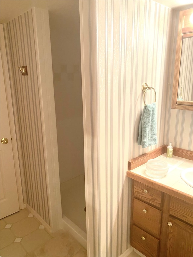 bathroom with walk in shower, vanity, and tile patterned floors