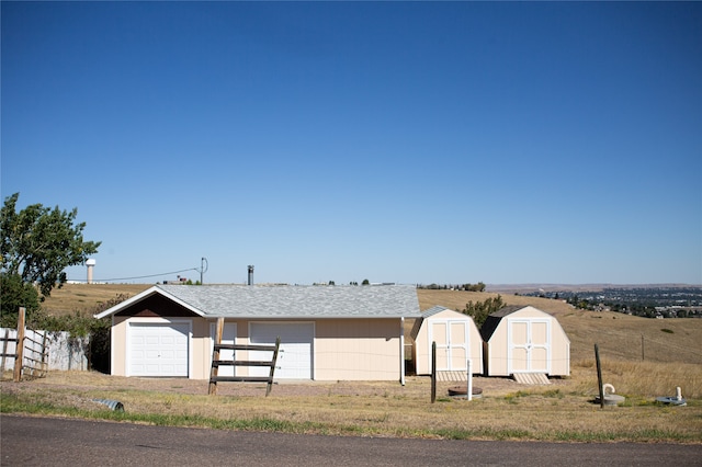 view of front of home featuring a garage, a storage unit, and a rural view