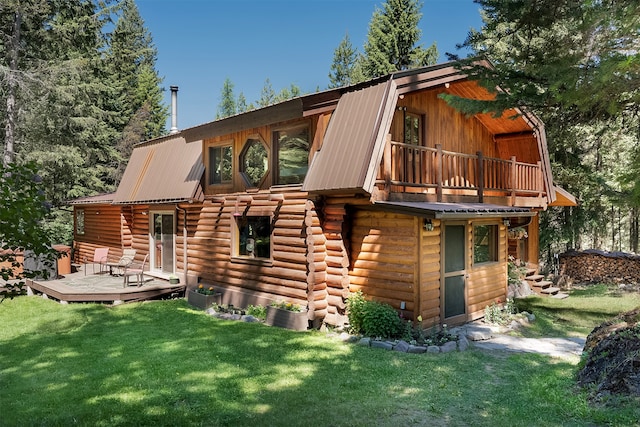 rear view of property featuring a balcony, a wooden deck, and a lawn