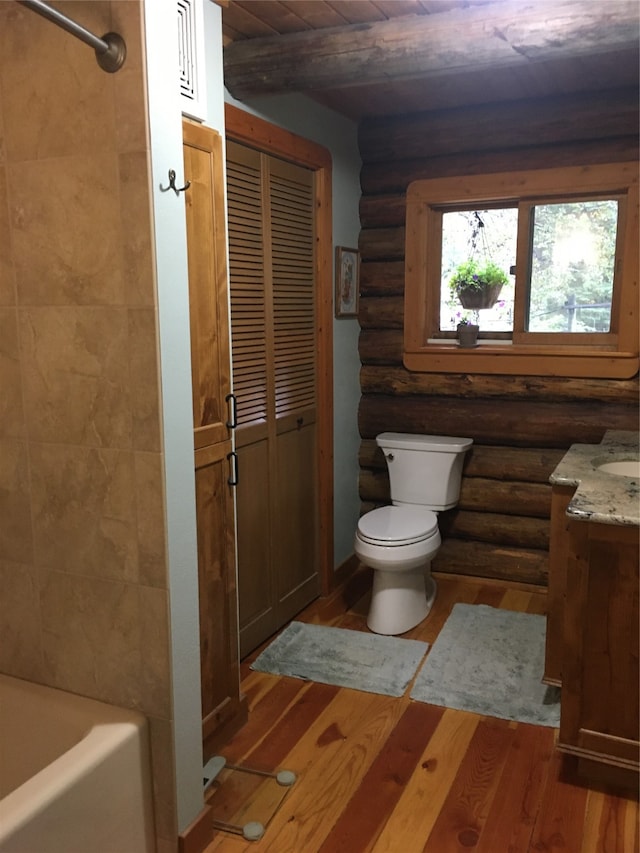 full bathroom featuring bathtub / shower combination, hardwood / wood-style floors, rustic walls, vanity, and toilet