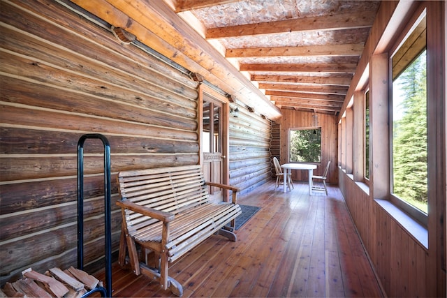 unfurnished sunroom featuring lofted ceiling with beams and a wealth of natural light