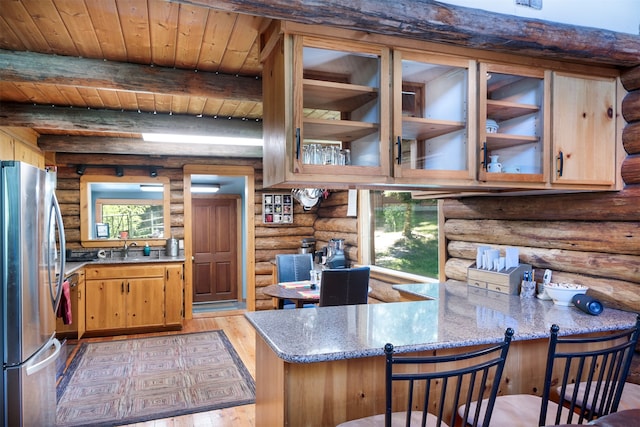 kitchen featuring wood ceiling, stainless steel refrigerator, kitchen peninsula, light hardwood / wood-style flooring, and rustic walls