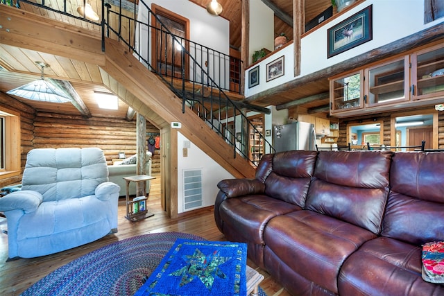 living room featuring beamed ceiling, log walls, hardwood / wood-style flooring, a high ceiling, and wooden ceiling