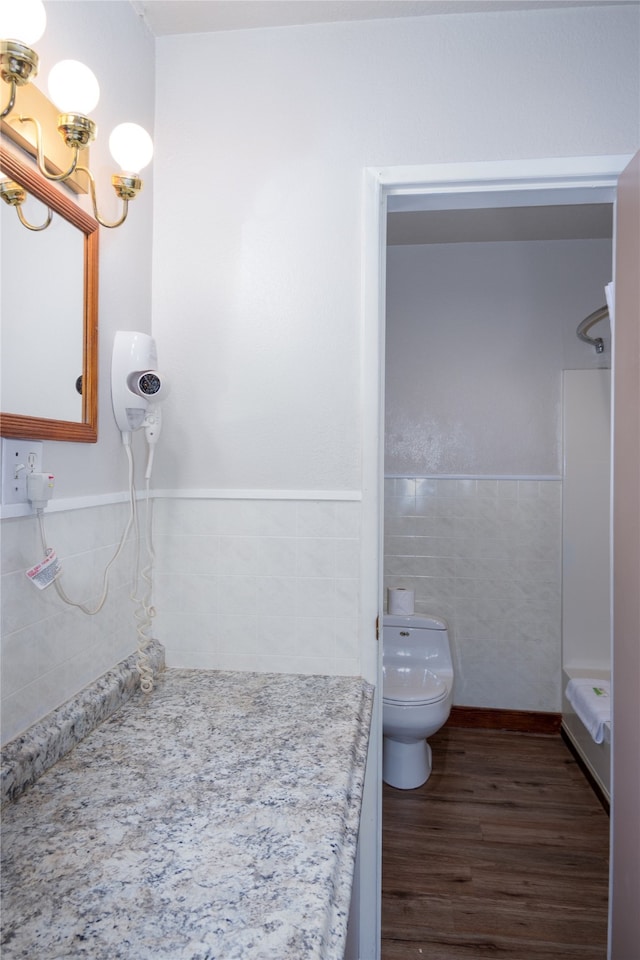 bathroom with wood-type flooring, walk in shower, tile walls, and toilet