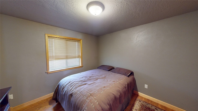 bedroom featuring hardwood / wood-style floors and a textured ceiling