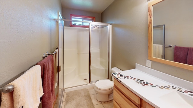 bathroom featuring tile patterned flooring, a shower with door, vanity, and toilet