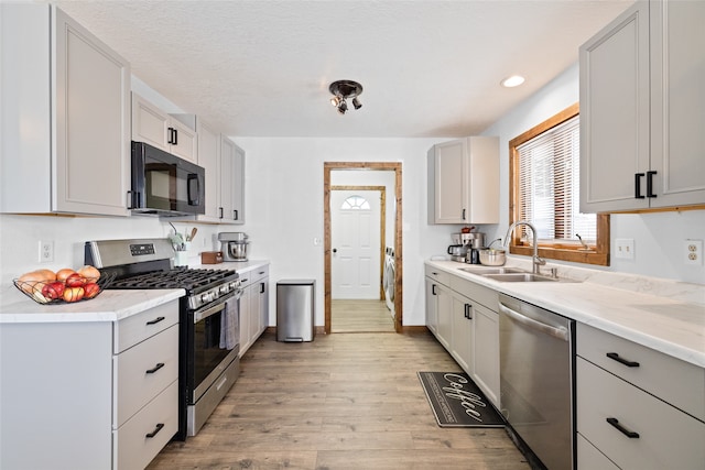 kitchen featuring sink, light hardwood / wood-style flooring, stainless steel appliances, and a textured ceiling