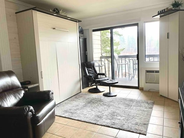 180 Vista Ln Unit 258, Bigfork, MT 59911 - living area with light tile patterned floors, a wall unit AC, and ornamental molding