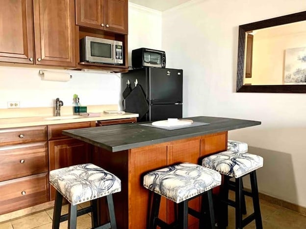 180 Vista Ln Unit 258, Bigfork, MT 59911 - kitchen featuring stainless steel microwave, freestanding refrigerator, a breakfast bar area, ornamental molding, and brown cabinetry