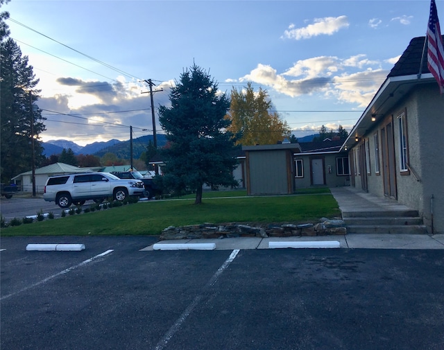 view of parking with a lawn and a mountain view