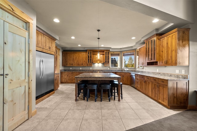 kitchen with appliances with stainless steel finishes, hanging light fixtures, a kitchen breakfast bar, light tile patterned flooring, and a kitchen island