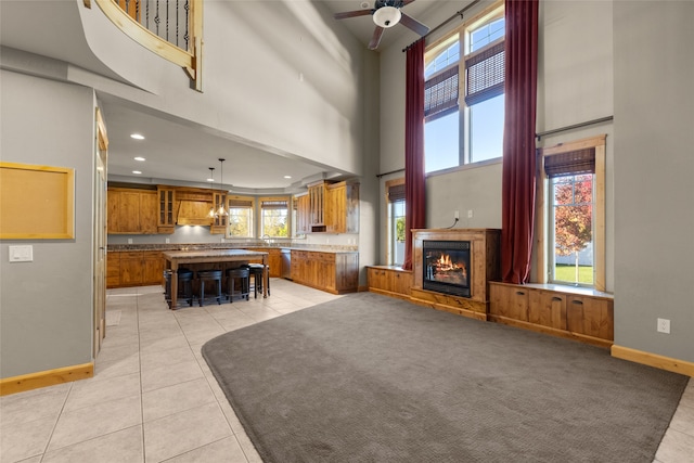 unfurnished living room featuring ceiling fan, light tile patterned flooring, sink, and a high ceiling