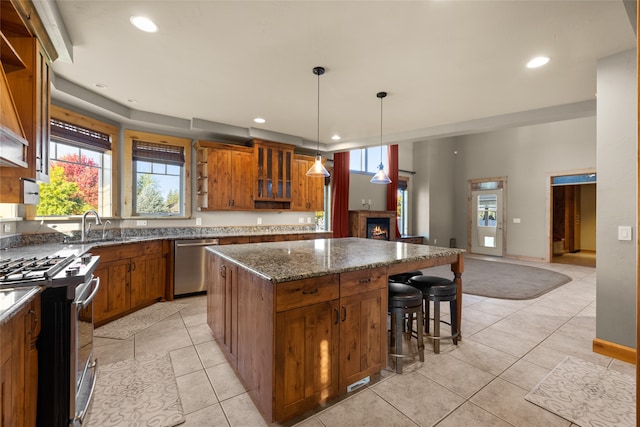 kitchen with light tile patterned flooring, appliances with stainless steel finishes, dark stone counters, and a center island