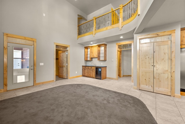 unfurnished living room with light carpet, a towering ceiling, and sink