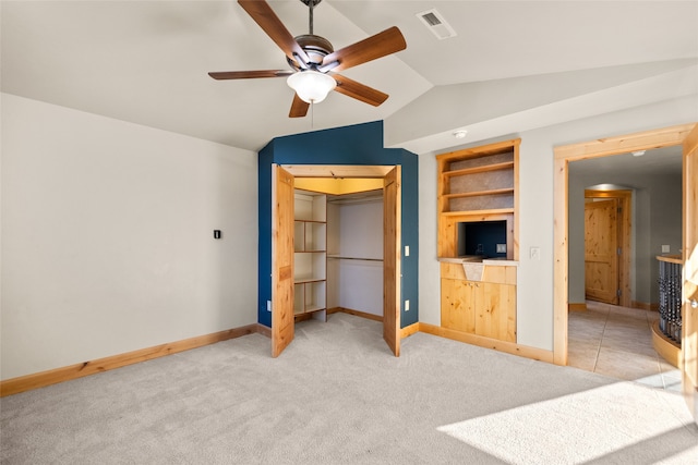 unfurnished bedroom featuring lofted ceiling, ceiling fan, light colored carpet, and a closet