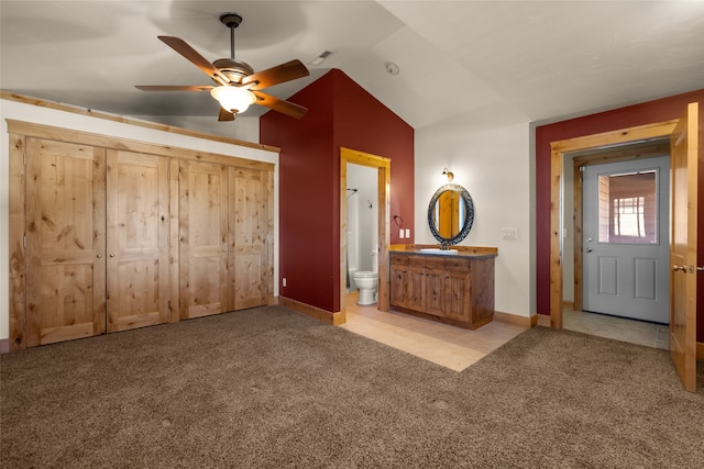 unfurnished bedroom featuring vaulted ceiling, a closet, ceiling fan, ensuite bathroom, and light carpet