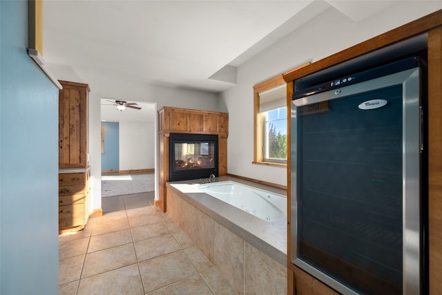 bathroom featuring ceiling fan, tiled bath, and tile patterned flooring