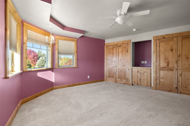 unfurnished bedroom featuring ceiling fan with notable chandelier and carpet