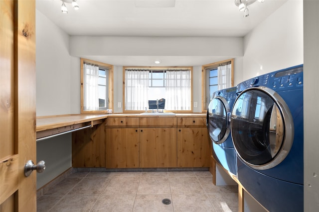 laundry area featuring light tile patterned floors, washer and clothes dryer, and sink