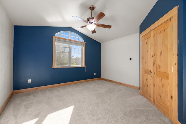 unfurnished bedroom with lofted ceiling, light carpet, ceiling fan, and a closet