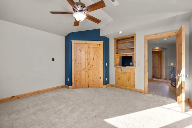 interior space featuring built in shelves, lofted ceiling, light carpet, and ceiling fan