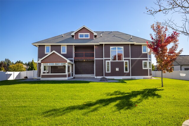 rear view of property with a patio, a yard, and a sunroom