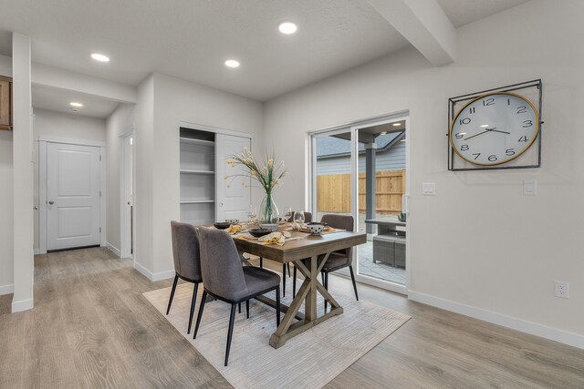 dining area with beam ceiling and light wood-type flooring