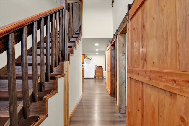 interior space with a barn door, a towering ceiling, and dark wood-type flooring