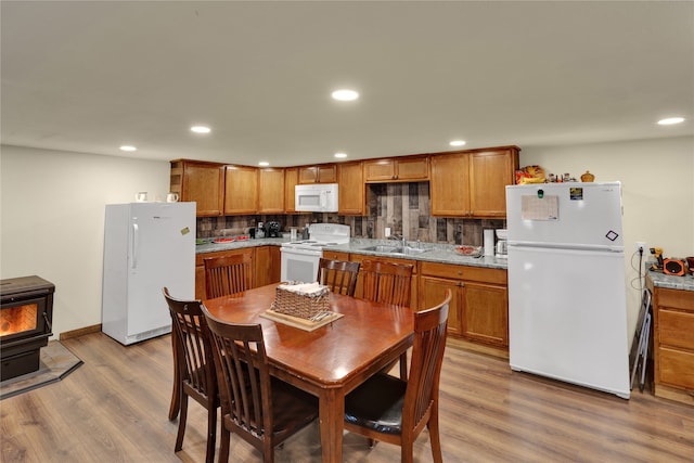 dining space featuring light wood-type flooring, a wood stove, and sink