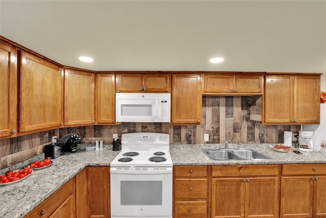 kitchen featuring light stone counters, sink, and white appliances