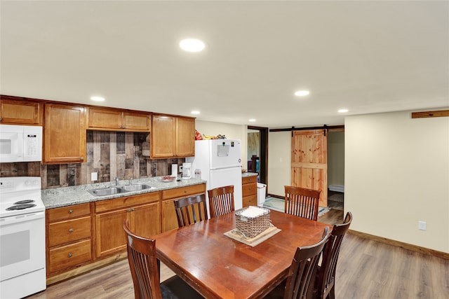 dining room with light wood-type flooring, a barn door, and sink