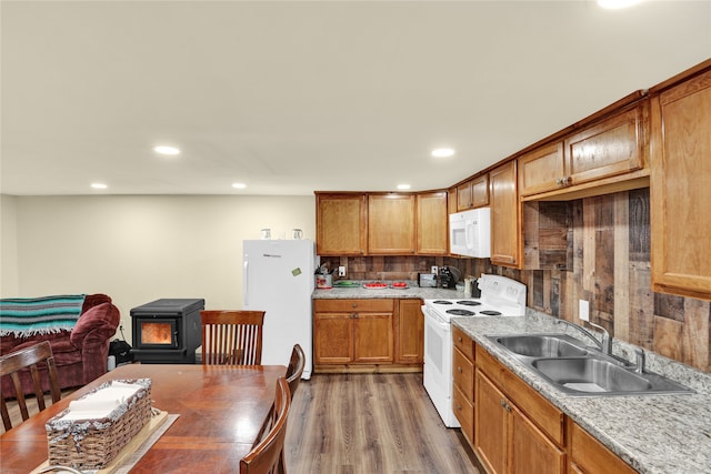 kitchen featuring backsplash, sink, wood-type flooring, and white appliances