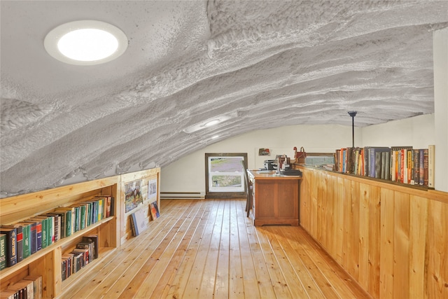 additional living space featuring a baseboard radiator, lofted ceiling, and light wood-type flooring