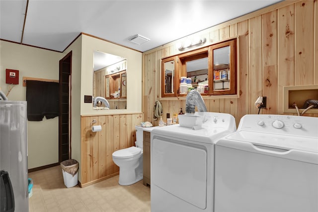 laundry area featuring washing machine and dryer and wooden walls