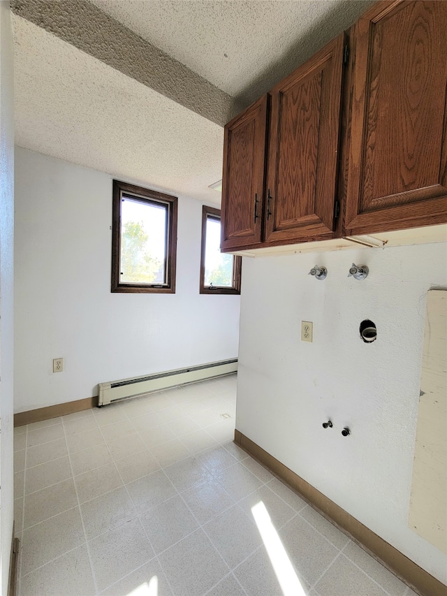 laundry room with a textured ceiling, cabinets, a baseboard radiator, and washer hookup