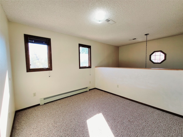 carpeted spare room with a wealth of natural light, a textured ceiling, and a baseboard heating unit