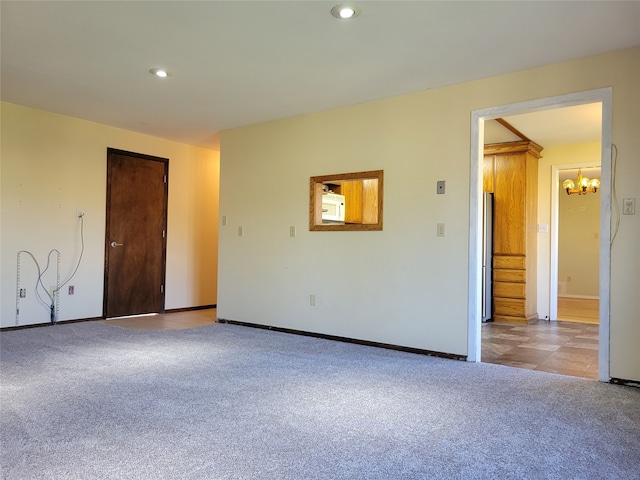 unfurnished room with light carpet and a chandelier