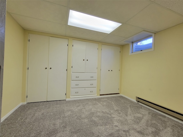 basement featuring a drop ceiling, light colored carpet, and baseboard heating