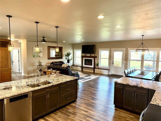 kitchen with dark hardwood / wood-style flooring, decorative light fixtures, sink, dishwasher, and light stone countertops