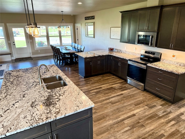 kitchen featuring dark hardwood / wood-style floors, stainless steel appliances, sink, hanging light fixtures, and an inviting chandelier