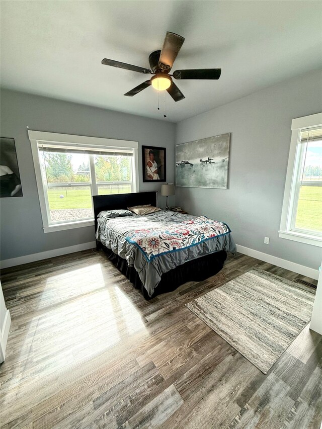 bedroom with hardwood / wood-style floors, multiple windows, and ceiling fan