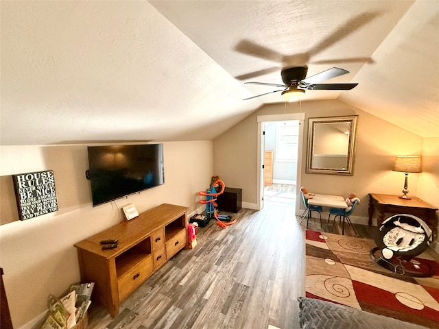 recreation room featuring lofted ceiling, ceiling fan, hardwood / wood-style floors, and a textured ceiling